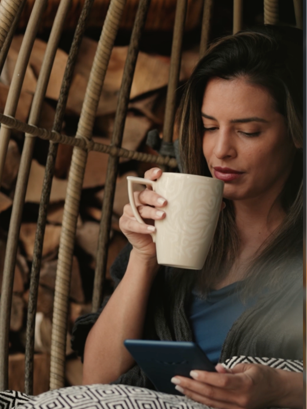 A woman with a warm drink in a hanging chair, taking a quiet moment